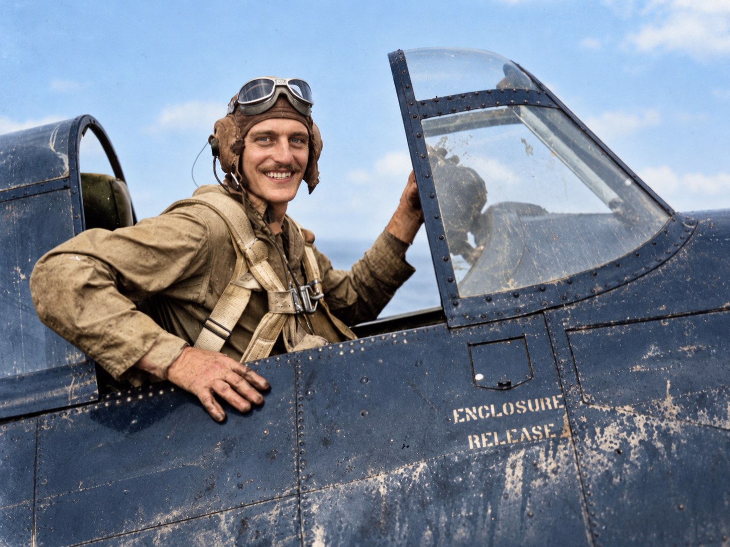 Vasileios C. Giftos smiling from the cockpit of an FM-2 Wildcat, in flying helmet and goggles