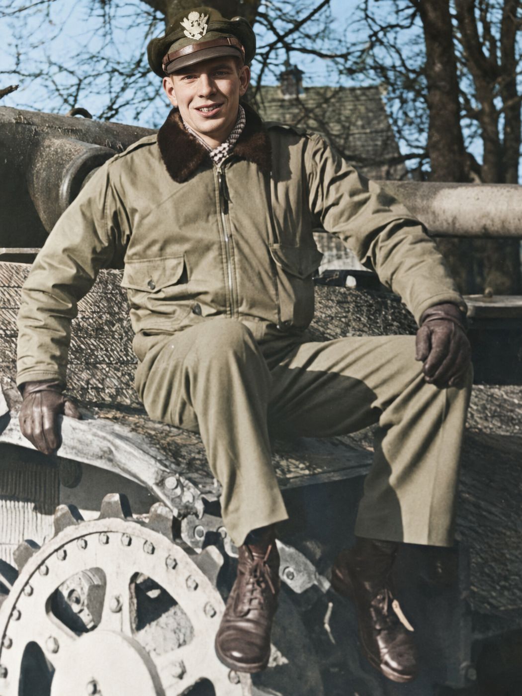 Kandis in officer's cap seated on the track of a tank